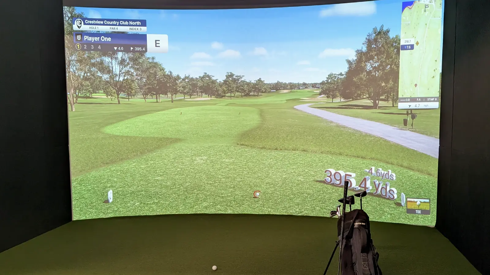 A private Pureshot simulator bay in Scripps Ranch, lit up with a fairway on the big curved screen, clubs and balls ready